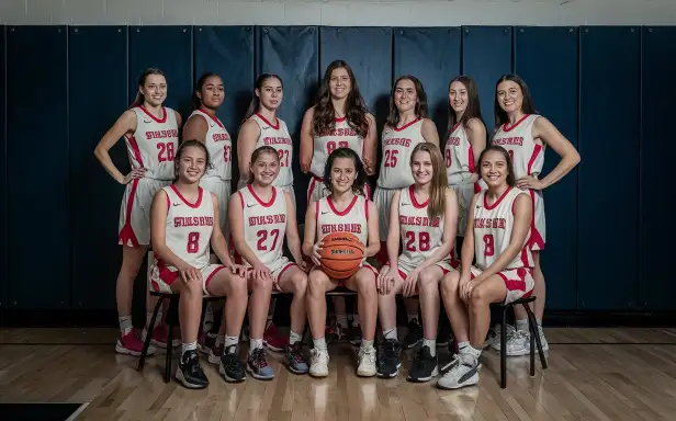 Women and girls basketball team poses together for a group photo, showcasing their unity and team spirit.