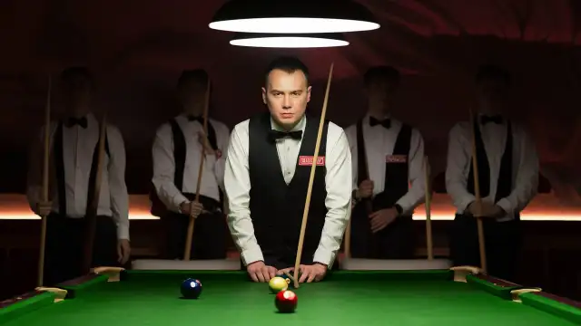 A man in a suit skillfully plays snooker, showcasing his focus and precision for a Pool Team Names event.