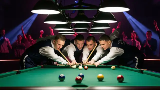 Four men engaged in a cool pool game in a dimly lit room, focusing intently on their shots and the green felt table.