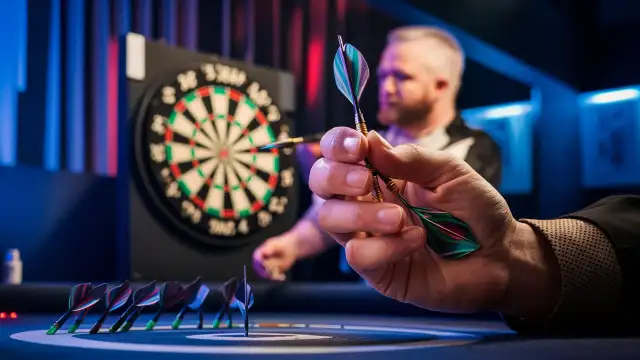 A man from the Cool Dart Team prepares to throw a dart at the dartboard, showcasing focus and precision in his stance.