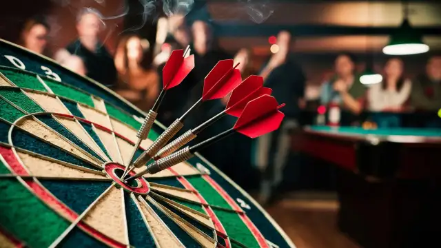 A dartboard with darts embedded, while the Clever Team enjoys a spirited game in the background with people gathered.