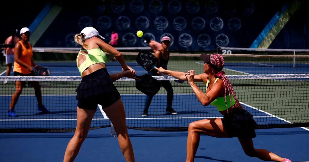 Two women engaged in a tennis match on a blue court, illustrating teamwork and strategy in "How to come up with your team.