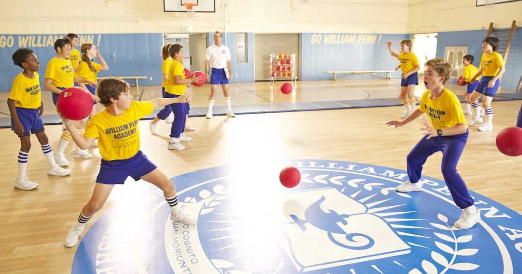 A group of young people engaged in a basketball game inside a gym, showcasing teamwork and athleticism.