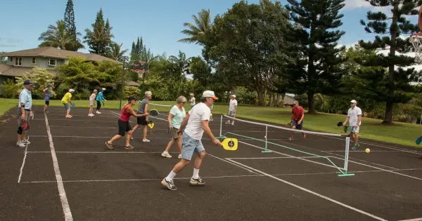 A group of individuals engaged in a lively tennis match on a court, showcasing teamwork and athleticism. Clever pickleball team names.