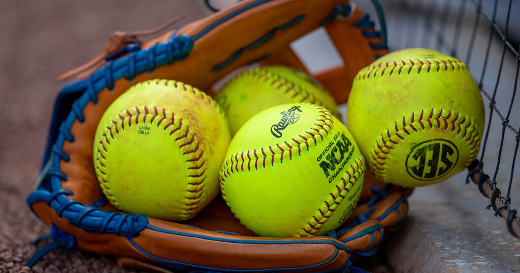 A softball nestled in a glove, accompanied by three additional balls, representing Beer League Softball Team Names.
